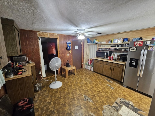 kitchen with wood walls, dark parquet flooring, appliances with stainless steel finishes, a textured ceiling, and ceiling fan