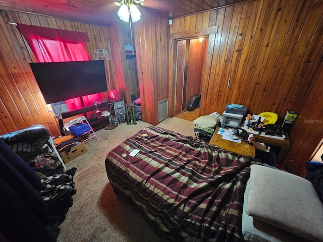 bedroom with wood walls, ceiling fan, and carpet floors