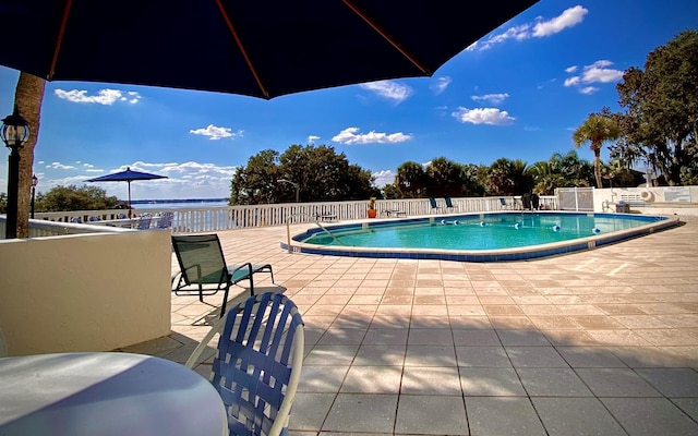 view of swimming pool featuring a water view and a patio area