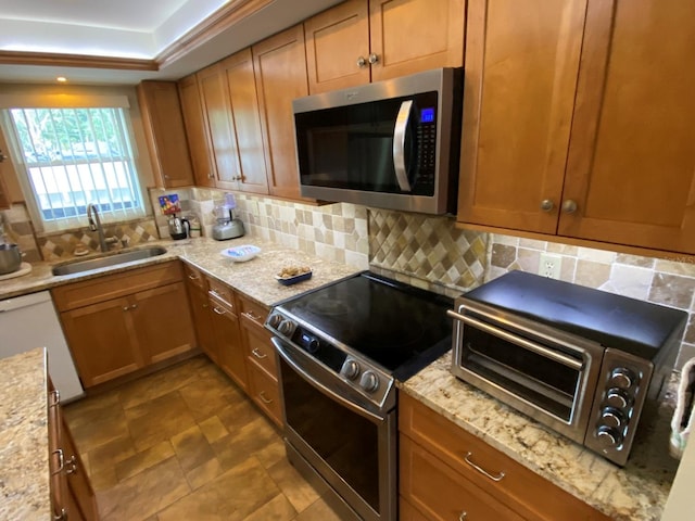 kitchen featuring light stone countertops, appliances with stainless steel finishes, decorative backsplash, and sink