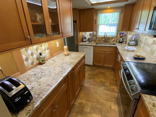 kitchen featuring decorative backsplash, light stone counters, sink, and stainless steel appliances