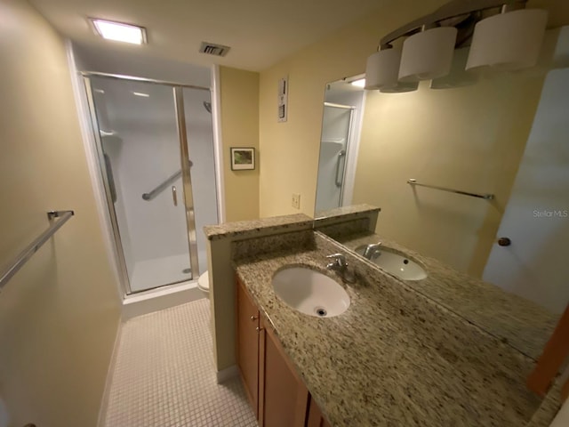 bathroom featuring tile patterned flooring, vanity, toilet, and a shower with shower door