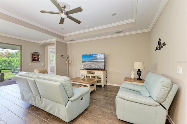 living room with ornamental molding, a tray ceiling, wood-type flooring, and ceiling fan