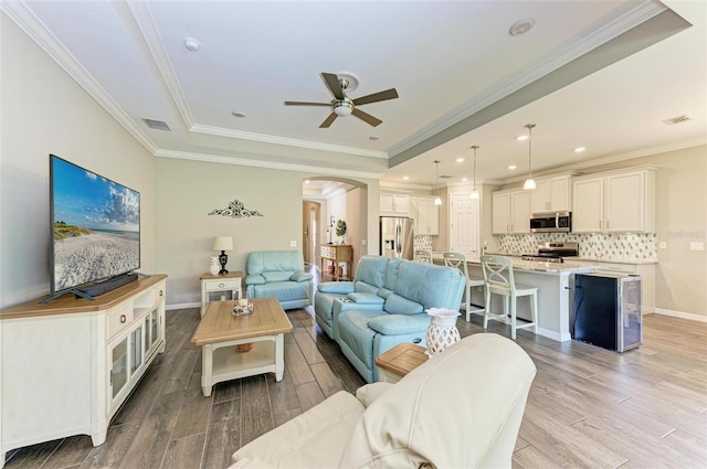 living room featuring crown molding, light wood-type flooring, and ceiling fan