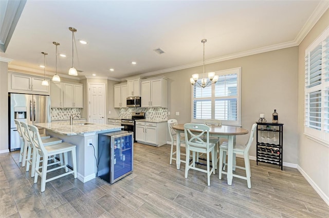 kitchen featuring light stone countertops, a kitchen island with sink, stainless steel appliances, and hanging light fixtures