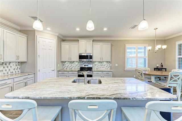 kitchen with appliances with stainless steel finishes, hanging light fixtures, and tasteful backsplash