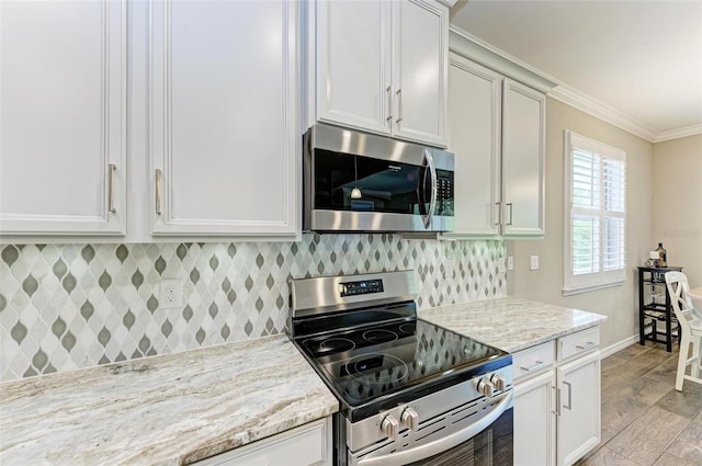 kitchen with light wood-type flooring, backsplash, stainless steel appliances, light stone counters, and ornamental molding