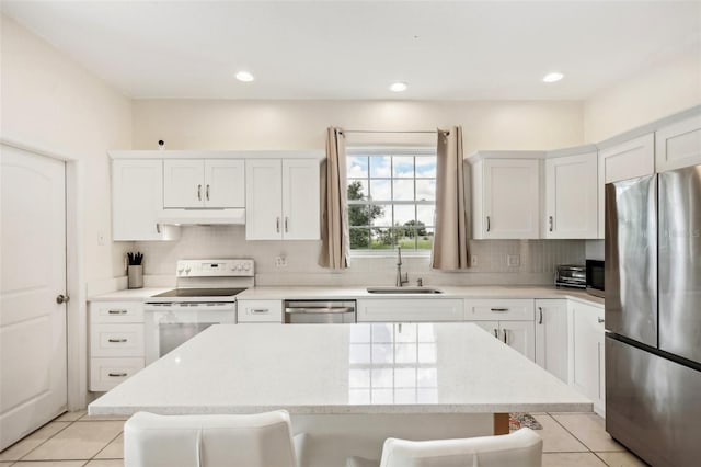 kitchen featuring sink, a breakfast bar, appliances with stainless steel finishes, white cabinets, and light tile patterned flooring