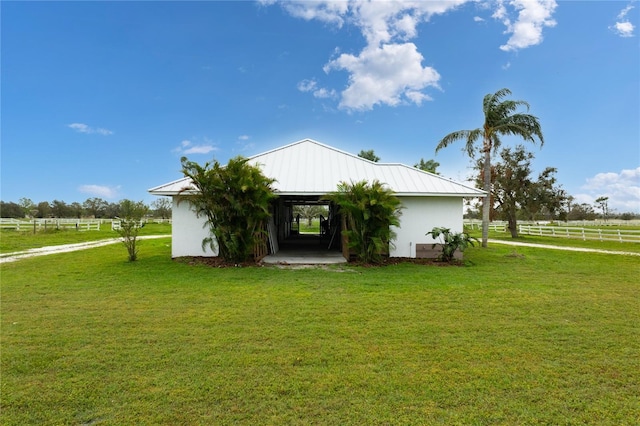 back of house featuring a rural view, a yard, and an outdoor structure