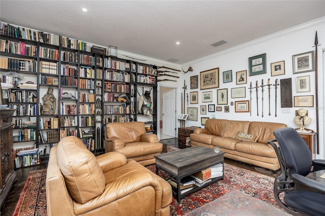 living room featuring crown molding, wood-type flooring, and a textured ceiling