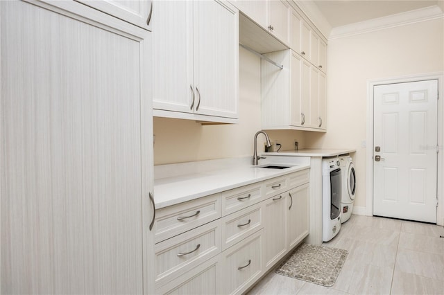 laundry area with sink, cabinets, light tile patterned floors, washing machine and clothes dryer, and crown molding