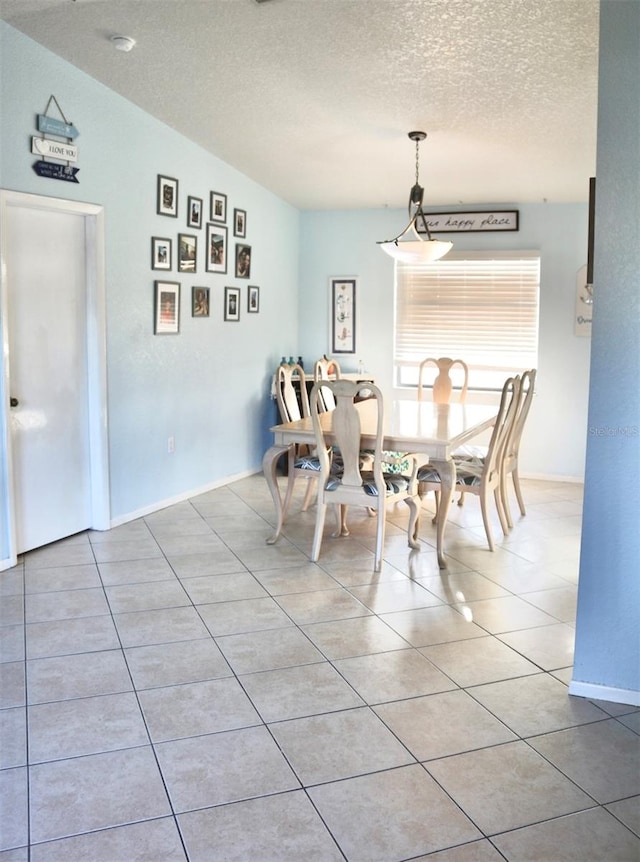 dining space featuring a textured ceiling, light tile patterned floors, and vaulted ceiling