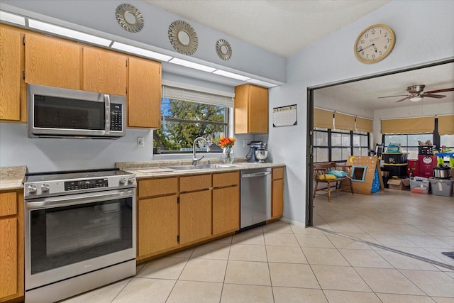 kitchen with light tile patterned floors, stainless steel appliances, a sink, a ceiling fan, and light countertops