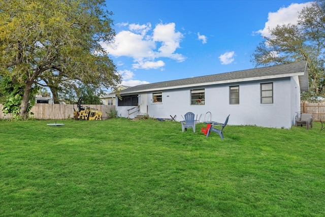 back of property featuring stucco siding, fence, and a yard