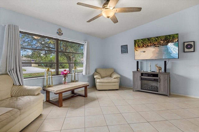 living room featuring baseboards, lofted ceiling, ceiling fan, a textured ceiling, and light tile patterned flooring