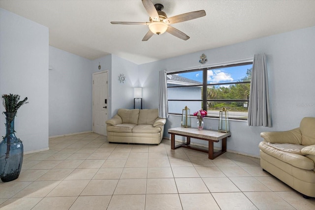 interior space featuring a ceiling fan, light tile patterned flooring, a textured ceiling, and baseboards