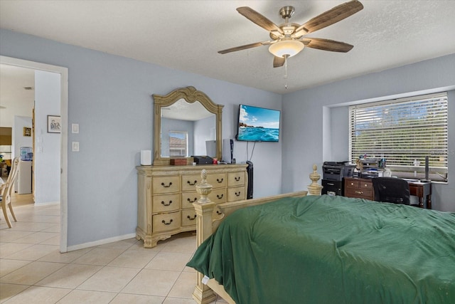 bedroom featuring light tile patterned floors, ceiling fan, baseboards, and a textured ceiling