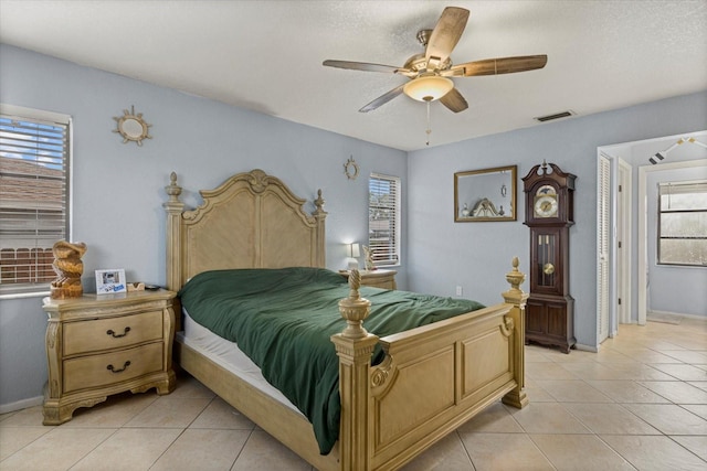 bedroom with ceiling fan, a textured ceiling, light tile patterned flooring, visible vents, and baseboards