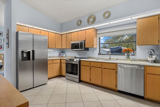 kitchen with lofted ceiling, stainless steel appliances, a sink, and light countertops