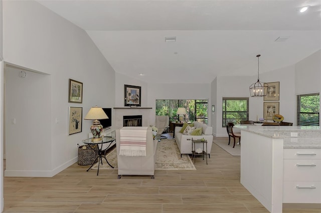 living room with light hardwood / wood-style flooring, a notable chandelier, and vaulted ceiling