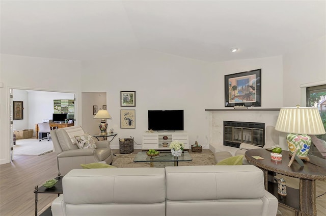 living room featuring vaulted ceiling, light hardwood / wood-style flooring, and a fireplace