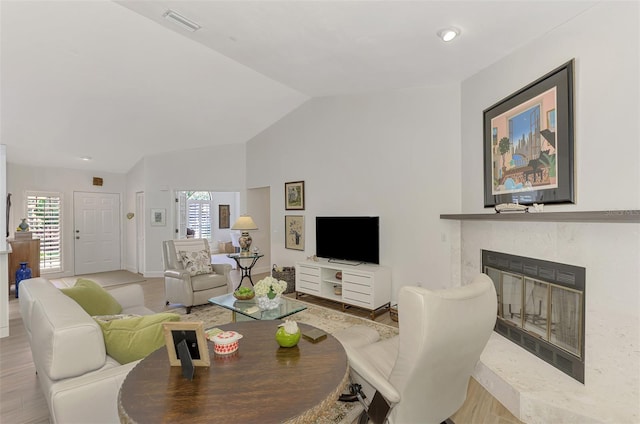 living room with lofted ceiling, a high end fireplace, and light wood-type flooring