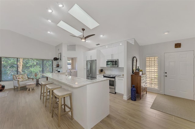 kitchen with appliances with stainless steel finishes, white cabinetry, a skylight, and a wealth of natural light