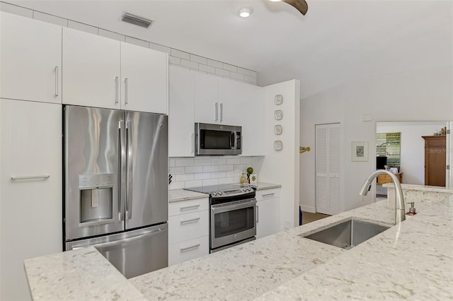 kitchen with white cabinets, light stone countertops, stainless steel appliances, and sink