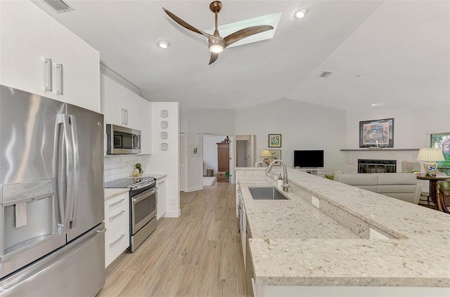 kitchen featuring light hardwood / wood-style flooring, sink, white cabinets, vaulted ceiling, and appliances with stainless steel finishes