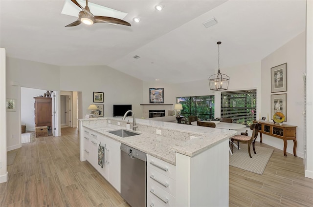 kitchen featuring sink, pendant lighting, stainless steel dishwasher, lofted ceiling with skylight, and white cabinetry