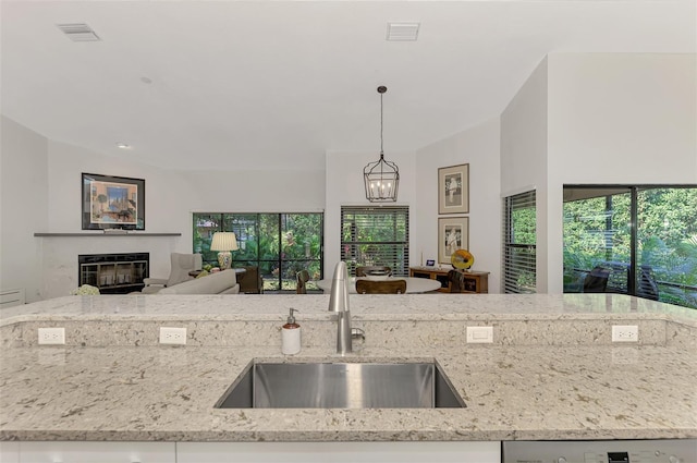 kitchen featuring light stone counters, sink, a wealth of natural light, and decorative light fixtures