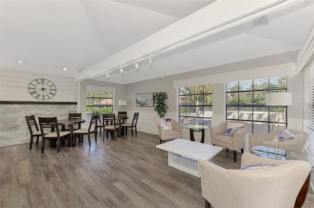 living room featuring hardwood / wood-style flooring, track lighting, lofted ceiling, and wood walls