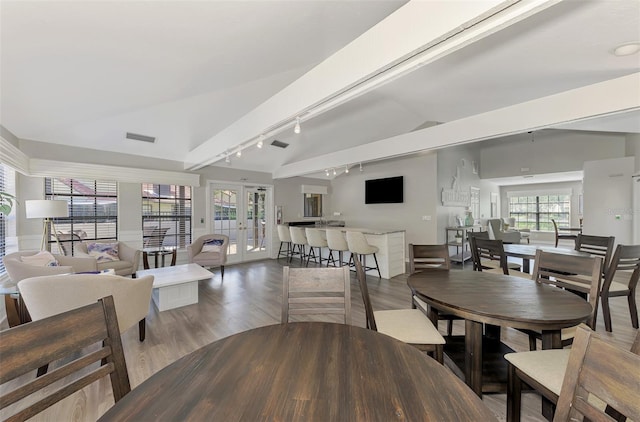 dining space featuring hardwood / wood-style floors, lofted ceiling, french doors, and rail lighting