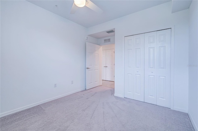 unfurnished bedroom with a closet, light colored carpet, and ceiling fan