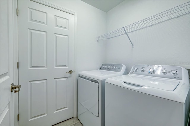 laundry room featuring washing machine and dryer and light tile patterned floors