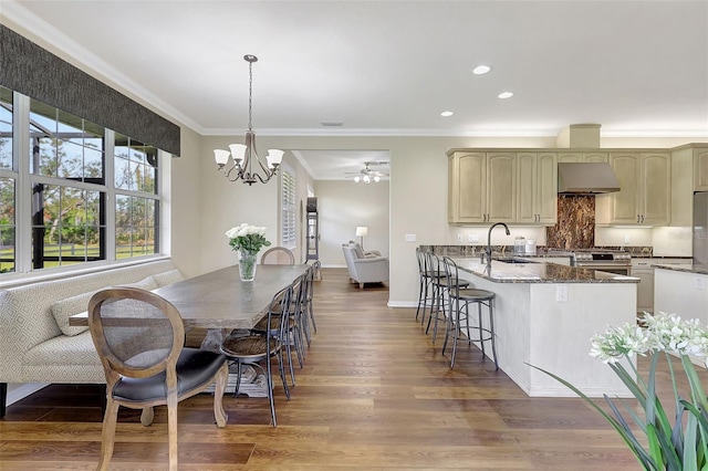 dining room with sink, hardwood / wood-style floors, ornamental molding, and ceiling fan with notable chandelier