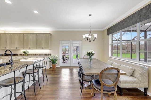 dining area featuring sink, crown molding, dark hardwood / wood-style floors, and an inviting chandelier