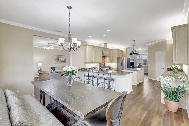 dining area with ornamental molding, ceiling fan with notable chandelier, and light wood-type flooring