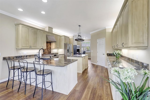 kitchen featuring wood-type flooring, sink, kitchen peninsula, pendant lighting, and stainless steel fridge with ice dispenser