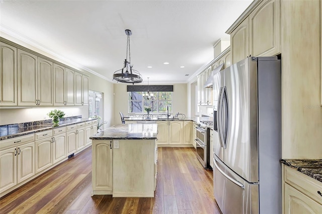 kitchen with appliances with stainless steel finishes, hardwood / wood-style floors, a center island, and cream cabinetry