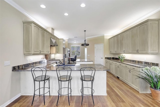 kitchen featuring kitchen peninsula, sink, light hardwood / wood-style floors, crown molding, and decorative light fixtures