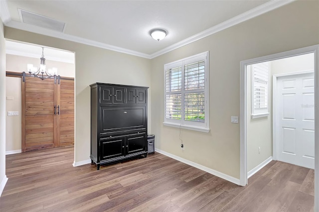 unfurnished bedroom featuring hardwood / wood-style floors, a barn door, and crown molding