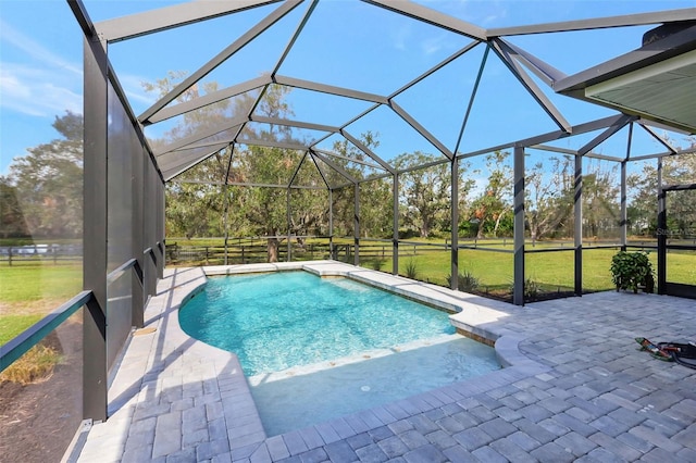 view of pool featuring a patio, glass enclosure, and a lawn