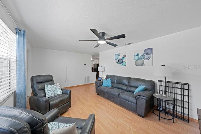 living room featuring hardwood / wood-style floors, ceiling fan, and a textured ceiling