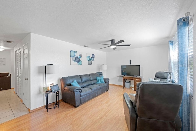 living room with a textured ceiling, hardwood / wood-style flooring, and ceiling fan