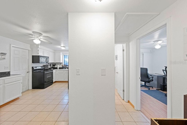 kitchen with electric range, ceiling fan, light tile patterned flooring, and white cabinets