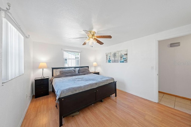 bedroom featuring ceiling fan, light hardwood / wood-style floors, and a textured ceiling