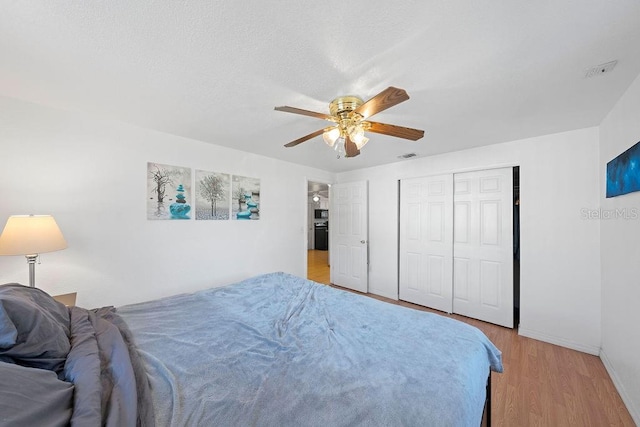 bedroom with ceiling fan, light hardwood / wood-style floors, and a closet