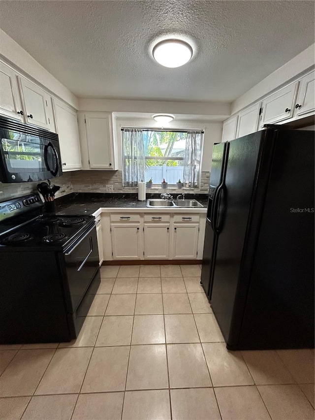 kitchen with a textured ceiling, sink, black appliances, light tile patterned floors, and white cabinetry