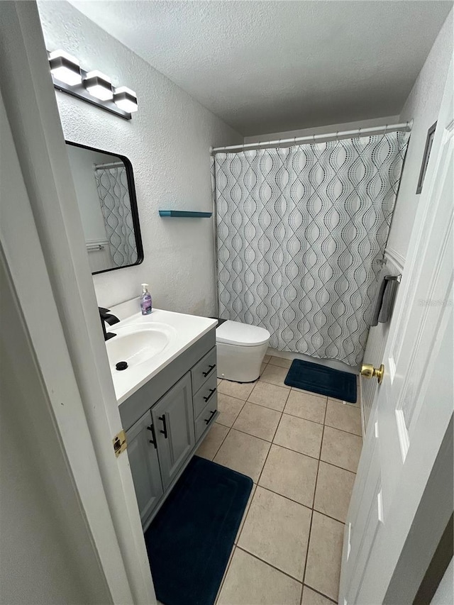 bathroom with vanity, tile patterned floors, toilet, a textured ceiling, and curtained shower